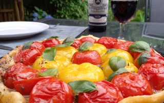 Eine Tatin Tomates auf einem Tisch neben einer Flasche Wein, die von einem Mietkoch mit Zutaten der französischen Küche zubereitet wurde.