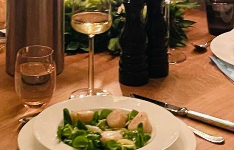 Salat mit Jacobsmuscheln auf einem gedeckten Esstisch mit Kerzenlicht