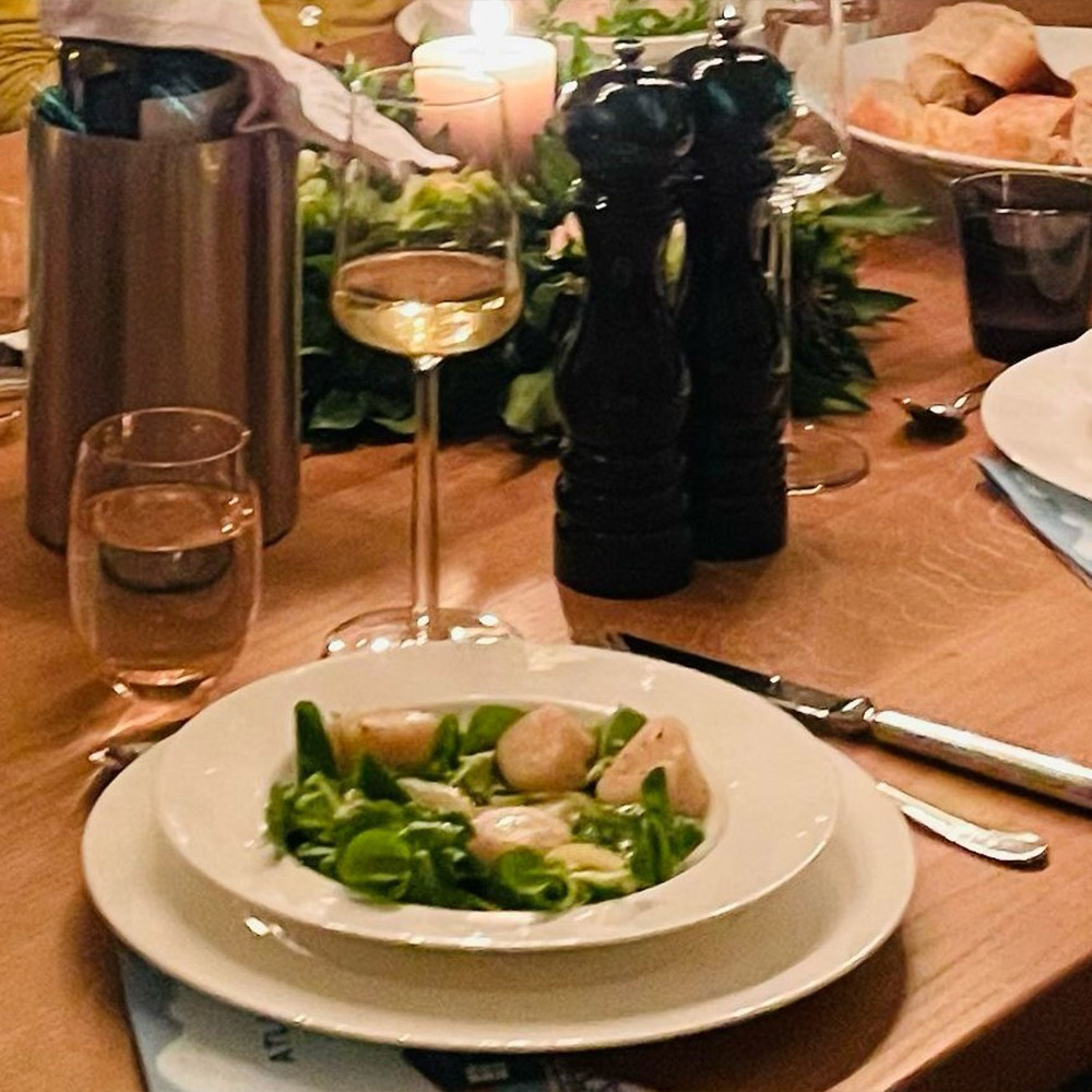 Salat mit Jacobsmuscheln auf einem gedeckten Esstisch mit Kerzenlicht