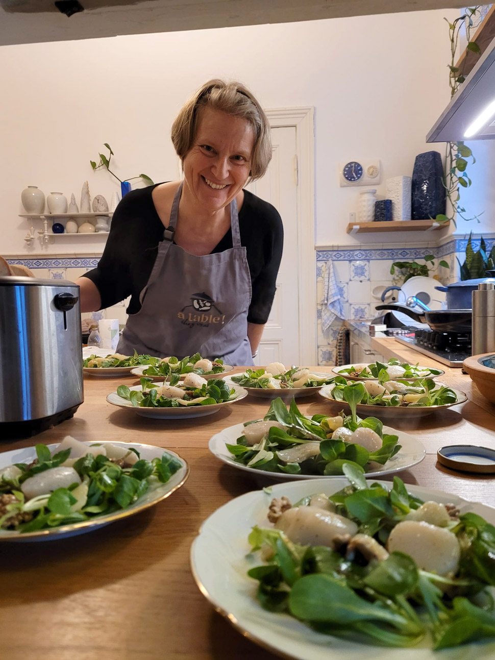 Benedicte Barth in der Kundenküche bereitet Salate mit Jakobsmuscheln vor und präsentiert diese auf Tellern