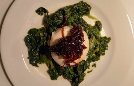 Burrata am Stück mit einer Haube konfierten Schalotten auf einem Spinatbett